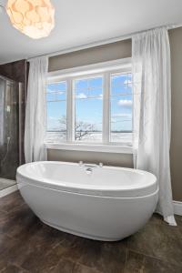a white bath tub in a bathroom with a window at A Getaway on Lake Champlain in Venise-en-Québec +39 photos