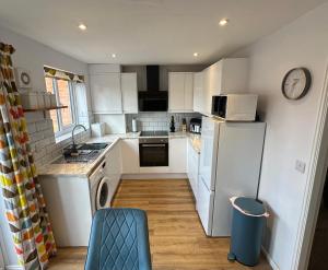 a small kitchen with white cabinets and a refrigerator at Serviced Accommodation, 3 Bed, allocated off road parking, Contractor Ready in Bedford