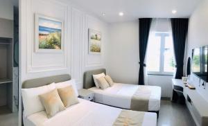 a hotel room with two beds and a desk at Happy House in Cam Lâm
