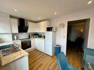 a kitchen with white cabinets and blue chairs at Serviced Accommodation, 3 Bed, allocated off road parking, Contractor Ready in Bedford +8 photos
