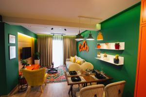 a living room with green walls and a table and chairs at Brilant Luxury Apartment in Gjirokastër