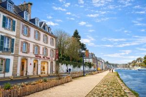 a cobblestone street next to a river with buildings at Hôtel Du Port in Morlaix
