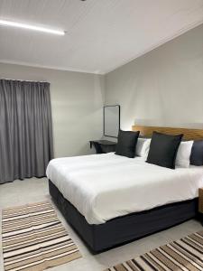 a bedroom with a large white bed with black pillows at Green Haven Waitara in Tzaneen