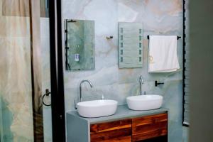 a bathroom with two sinks and two mirrors at MILLENIUM SUITES - Piscine privée in Yamoussoukro