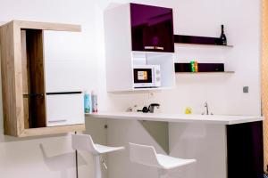 a kitchen with a sink and two white chairs at MILLENIUM SUITES - Piscine privée in Yamoussoukro