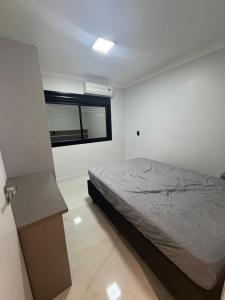 a white bedroom with a bed and a window at Casa da Palmeira com Piscina in Piratuba +8 photos