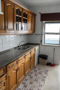 a kitchen with wooden cabinets and a sink and a window at Cozy Room in Corroios Near Beach & Lisbon - Quarto Acolhedor em Corroios Perto da Praia e Lisboa in Corroios