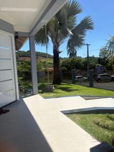 a palm tree in front of a house with a garage at Casa da Palmeira com Piscina in Piratuba