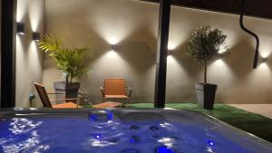 a hot tub in a room with chairs and plants at Love room- Le Cocon Osé in Autun