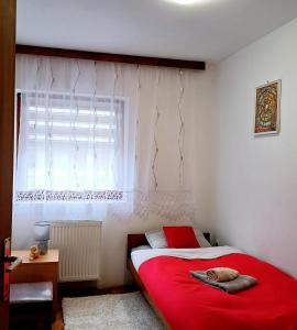 a bedroom with a red bed and a window at Sunstation in Šarengrad