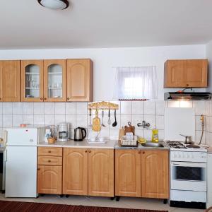 a kitchen with wooden cabinets and white appliances at Sunstation in Šarengrad