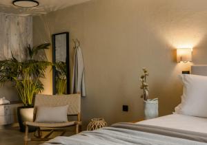 a bedroom with a bed and a chair and plants at Nomāde Agora Suites - Lixouri Town Centre, Kefalonia - Private Balconies in Lixouri +19 photos