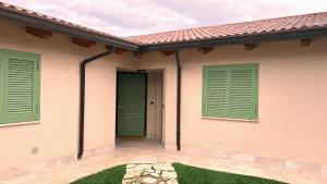 a house with green shutters and a patio at Residence Il Casolare in Piedimonte San Germano