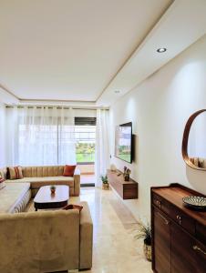 a living room with a couch and a table at Pool view apartment, beach access, nature & quiet in Mansouria