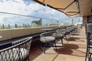 a row of tables and chairs on a rooftop patio at Motto By Hilton Recife in Recife +75 photos
