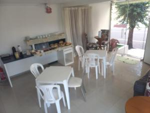 a living room with white tables and white chairs at Pousada Romelandia in Romelândia