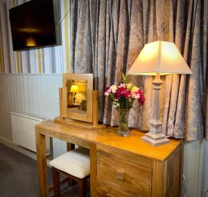 a table with a lamp and a mirror and flowers at Sibton White Horse Inn in Saxmundham