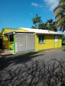 a yellow and green house with a palm tree at Gîte HIBISCUS in Saint-François