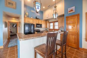 a kitchen with wooden cabinets and a island with two chairs at Happy Dog Days - Nags Head MP 11, Ocean View, 50 Yds to Beach, Elevator, Pool, Hot Tub, Pets OK, Flex Stays in Nags Head