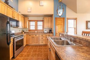 a kitchen with wooden cabinets and a stainless steel sink at Happy Dog Days - Nags Head MP 11, Ocean View, 50 Yds to Beach, Elevator, Pool, Hot Tub, Pets OK, Flex Stays in Nags Head