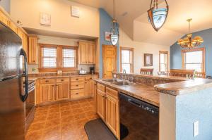 a kitchen with wooden cabinets and a black refrigerator at Happy Dog Days - Nags Head MP 11, Ocean View, 50 Yds to Beach, Elevator, Pool, Hot Tub, Pets OK, Flex Stays in Nags Head