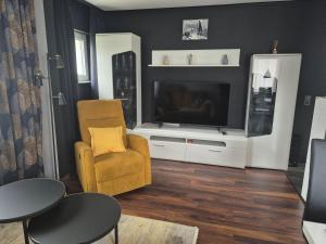 a living room with a yellow chair and a television at Ferienwohnung Am Schiff in Eberbach in Eberbach