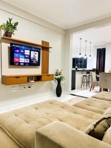 a living room with a bed and a tv on a wall at APË GOLD NO CENTRO DA CIDADE COM AR E CAMA KINg in Formosa