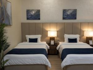 a hotel room with two beds and two lamps at sea breeze RAK in Ras al Khaimah