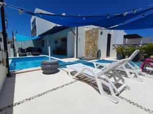 two white lawn chairs sitting next to a swimming pool at Nautica Apartment-4 guests and shared pool in Isla Mujeres