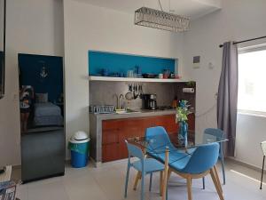 a kitchen with a glass table and blue chairs at Nautica Apartment-4 guests and shared pool in Isla Mujeres