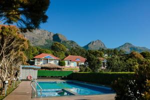 a house with a swimming pool with mountains in the background at Holiday Heaven Munnar in Chinnakanal