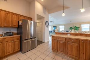 a kitchen with wooden cabinets and a stainless steel refrigerator at Serenity in Nags Head - MP 11, Oceanfront, Ocean View, Pool, Hot Tub, Pets OK, YR Flex Stays in Nags Head