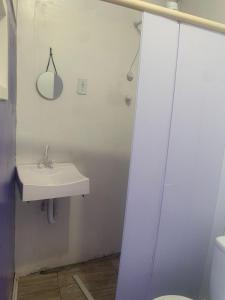 a white bathroom with a sink and a shower at Pousada Romelandia in Romelândia