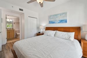 a bedroom with a white bed and a bathroom at Sunsets & Coastal Vibes Treasure Island Stay in St. Pete Beach