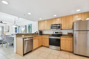 a kitchen with wooden cabinets and stainless steel appliances at Sunsets & Coastal Vibes Treasure Island Stay in St. Pete Beach