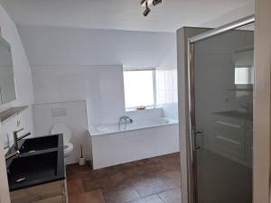 a bathroom with a tub and a toilet and a sink at Liroja's Vakantiehuis in Vlagtwedde +18 photos