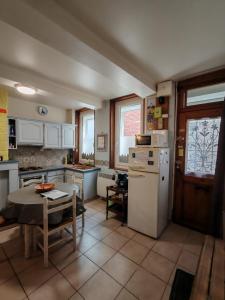 a kitchen with a table and a white refrigerator at L'arras Square maison au calme avec deux chambres in Arras