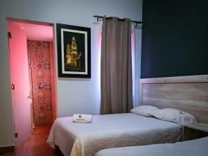a bedroom with two beds and a pink light at Hotel San Miguel in Morelia