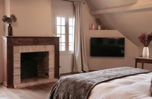 a bedroom with a fireplace and a flat screen tv at CASAMAAS in Les Basses Masures