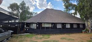 a black house with a thatched roof at Buffelslaagte at the Vaal in Oranjeville