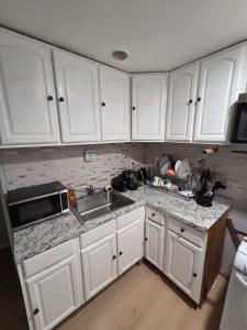 a kitchen with white cabinets and a sink at Executive private room in Irvington +8 photos