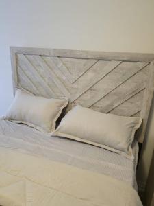 a bed with a wooden headboard and two pillows at Modern 3BR FriendlyTown Home in Paris