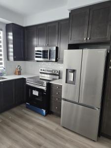 a kitchen with black cabinets and a stainless steel refrigerator at Modern 3BR FriendlyTown Home in Paris