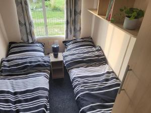 two beds in a small room with a window at Domki nad Szóstakiem in Orzechowo