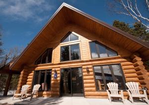 a cabin with white chairs in front of it at Le Chalet Bois Rond Relax in Saint-Tite-des-Caps