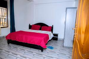 a bedroom with a large bed with red pillows at Global Village Apartment in Kigali +1 photo