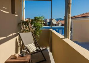 a chair sitting on a balcony with a view at Nomāde Agora Suites - Lixouri Town Centre, Kefalonia - Private Balconies in Lixouri