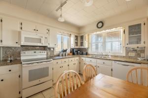 a kitchen with white cabinets and a wooden table at Jacks - Nags Head MP 12, Oceanfront, Ocean Views, Huge Deck, YMCA Pkg in Nags Head
