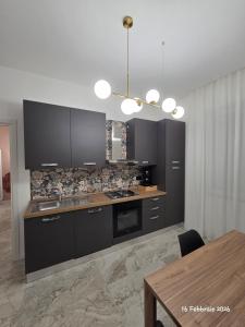 a kitchen with black cabinets and a wooden table at B&B Domus morfeo Caserta in Caserta