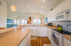 a kitchen with white cabinets and a stove top oven at It's A Shore Thing - Nags Head MP 11.5, Ocean View, 130 Yds to Beach, Pool, Hot Tub, Rec Room in Nags Head